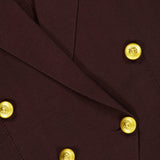Close-up of the Amelia Knit Blazer by L’AGENCE, a dark brown tailored piece accented with shiny gold engraved buttons. The fabric texture and detailed button design are clearly visible.