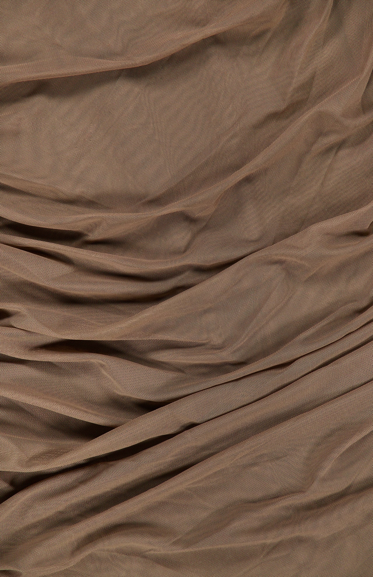 The Anya Shirred Midi Dress by L’AGENCE features a brown, softly wrinkled fabric with gentle folds and creases that create a beautifully textured surface. The lightweight, slightly sheer stretch mesh gives this sleeveless midi dress a delicate and elegant look.