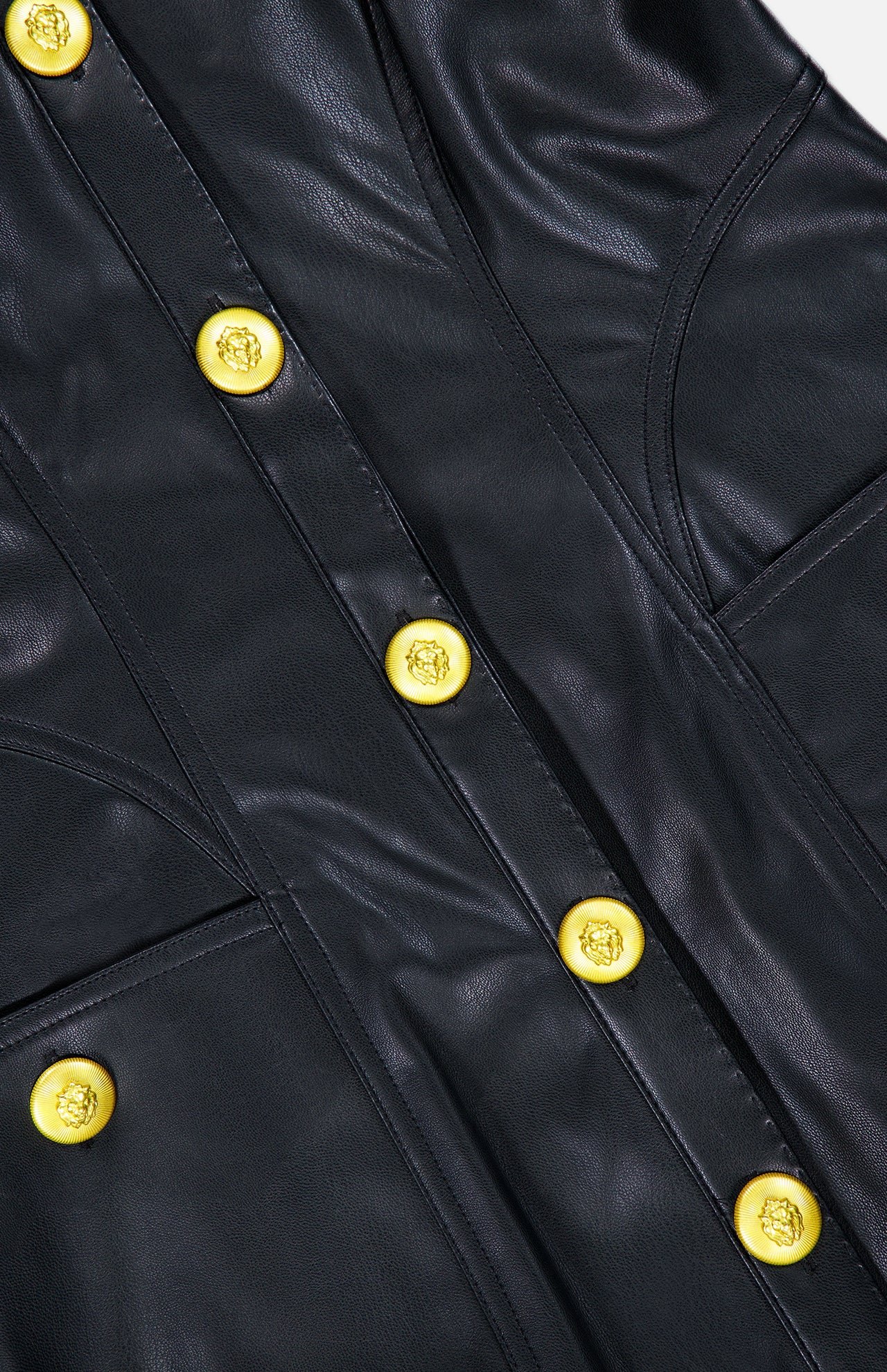 Close-up of the L’AGENCE Apolline Collar Racer Mini Dress in black vegan leather, showcasing detailed stitching, visible seam pockets, and bold shiny gold embossed buttons.