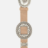 The Austin Concho Medlin Belt by L'AGENCE is a light brown leather statement piece with ornate silver-toned engraved concho accents in round and square shapes, decorative edging, and intricate patterns.