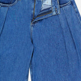 A pair of Chayse High Rise Super Wide Leg Jeans in Towson by L’AGENCE, featuring blue denim with a partially unzipped fly and open button that reveals the inner waistband and signature brand tag.