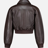 The Clotilde Leather Bomber Jacket by L’AGENCE is a cropped dark brown leather piece featuring a wide collar, long sleeves, and ribbed cuffs and hem, all styled in a classic bomber silhouette. It is pictured from the back against a plain white background.