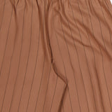 Close-up of the Connie Drawstring Pinstripe Trouser by L'AGENCE, showcasing brown fabric with thin vertical black pinstripes, an elastic drawstring waistband, and a smooth texture. These wide leg trousers can be styled with the matching blazer for a coordinated look.