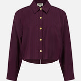 The Cosette Crop Hi Low Shirt by L'AGENCE is a long-sleeve burgundy pinstripe button-up with a pointed collar, gold-tone coin buttons, a slightly cropped high-low hem, and a boxy fit.