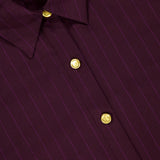 Close-up of the L’AGENCE Cosette Crop Hi Low Shirt, featuring deep purple and burgundy pinstripes, gold-tone coin buttons, a pointed collar, and a modern cropped high-low hem.