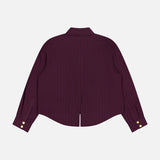 The L'AGENCE Cosette Crop Hi Low Shirt is shown from the back, featuring burgundy pinstripes, a straight collar, gold-tone coin buttons at the cuffs, and a cropped high-low hem with a center slit.