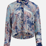 The Cosette Crop Hi Low Shirt by L’AGENCE is a long-sleeve button-up blouse showcasing a vibrant paisley pattern in blue, light blue, and red hues. This tailored top features a classic collar with a slightly cropped high-low hem for a modern, boxy silhouette.