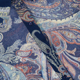 Close-up of the L’AGENCE Cosette Crop Hi Low Shirt, featuring a blue and red paisley pattern, dark buttons, and a pointed collar. The fabric label is visible in the top left corner.