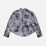 The Cosette Crop Hi Low Shirt by L’AGENCE is a long-sleeve paisley print blouse, featuring a multicolored pattern in blue, pink, and cream tones. Displayed flat with the back facing up against a white background, this tailored shirt offers a modern twist on a classic style with its cropped high-low hem.