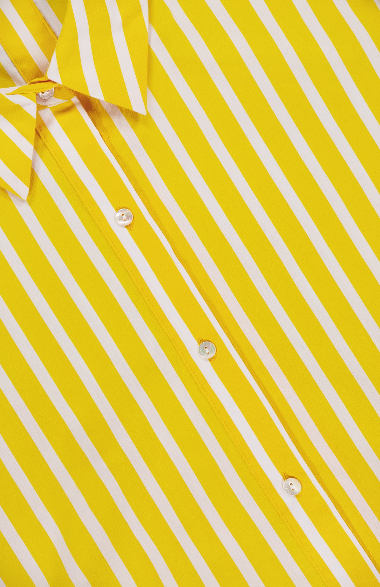 Close-up of the Cosette Crop Hi Low Shirt by L'AGENCE—yellow with white diagonal stripes, white buttons, and a collar. Crafted from organic cotton, this tailored shirt blends summer comfort and style.