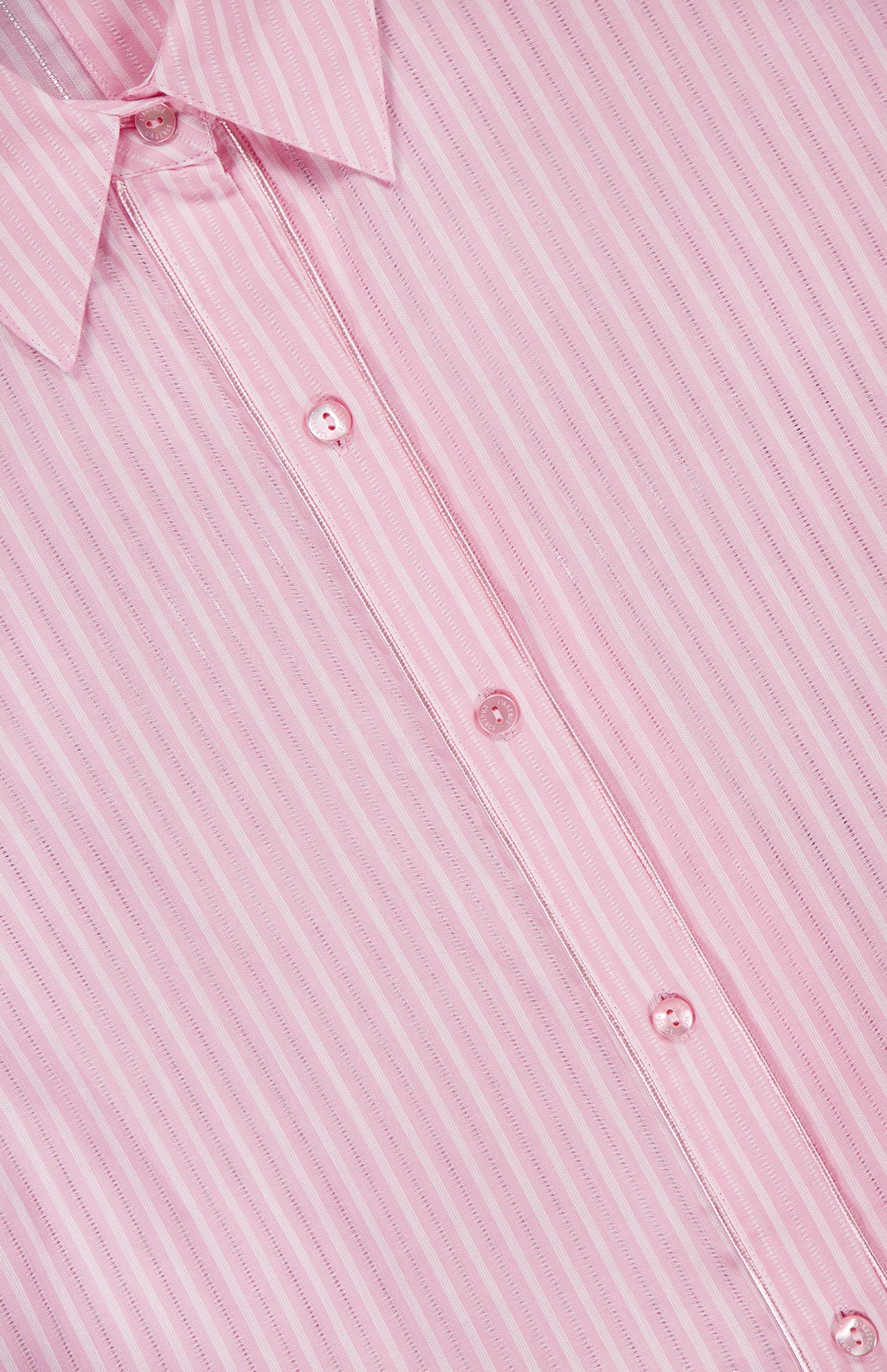 Close-up of the L'AGENCE Cosette Cropped Back Slit Shirt, featuring soft cotton in light pink with subtle vertical stripes, white buttons, and the collar visible at the top left.