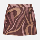 The Cyra Low Rise Mini Skirt by L'AGENCE features front buttoned flap pockets and an abstract swirl print in brown, pink, and tan, perfectly capturing the iconic 70s retro style.