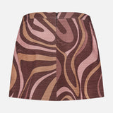 The Cyra Low Rise Mini Skirt by L'AGENCE features a retro wavy abstract swirl print in brown, pink, and beige tones, with a visible back zipper, shown laid flat on a white background.