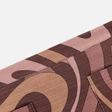 A detailed close-up of the Cyra Low Rise Mini Skirt by L'AGENCE showcases its pink, brown, and tan abstract swirl print fabric, highlighted by visible stitching and a metal snap button on the lower left.