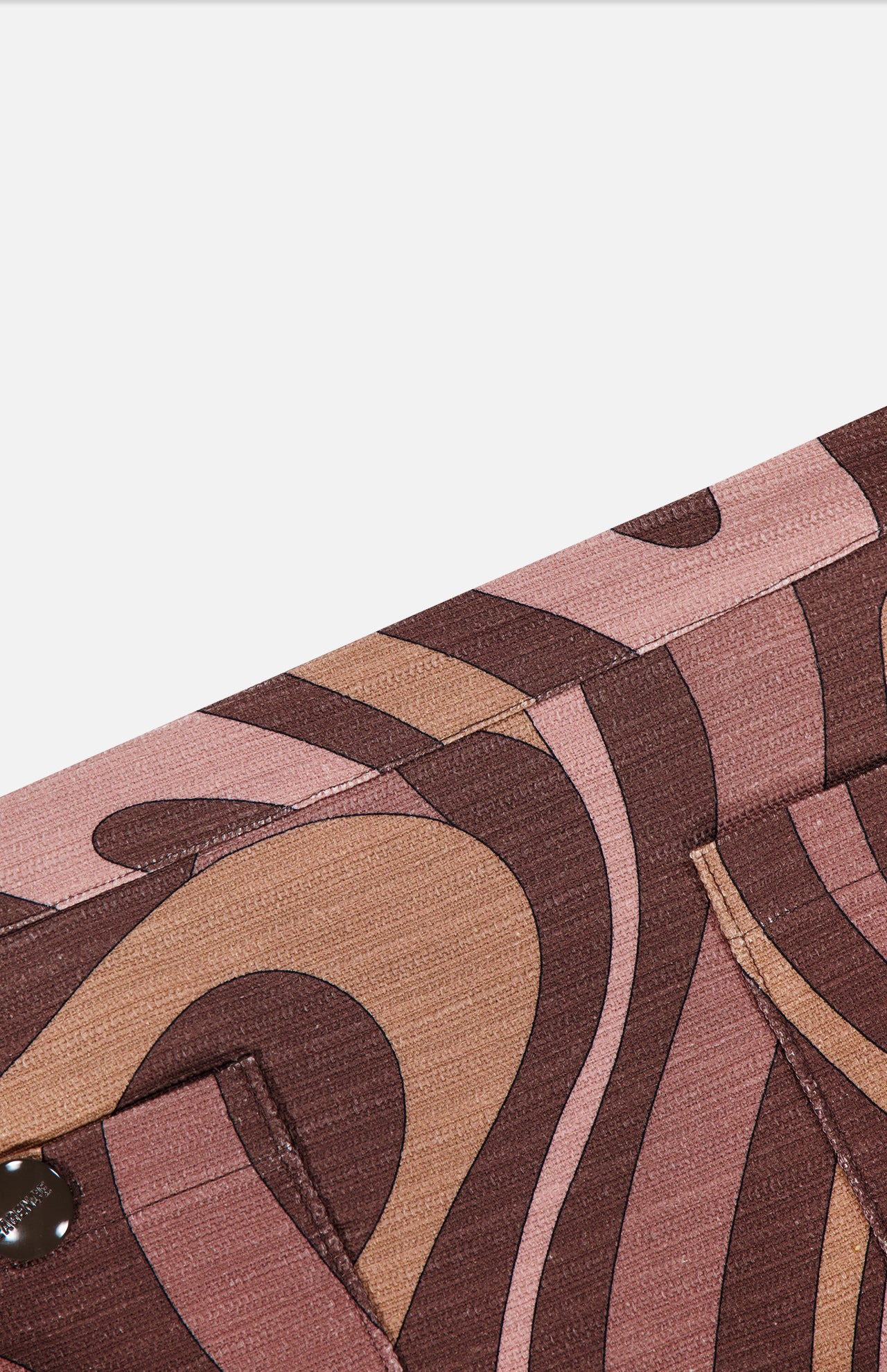 A detailed close-up of the Cyra Low Rise Mini Skirt by L'AGENCE showcases its pink, brown, and tan abstract swirl print fabric, highlighted by visible stitching and a metal snap button on the lower left.