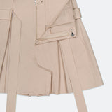 The Damira Paperbag Short by L'AGENCE features a beige pleated design with an open front zipper, visible button, two long self-tie belts, and a structured waistband, offering a tailored look inspired by high-rise shorts.