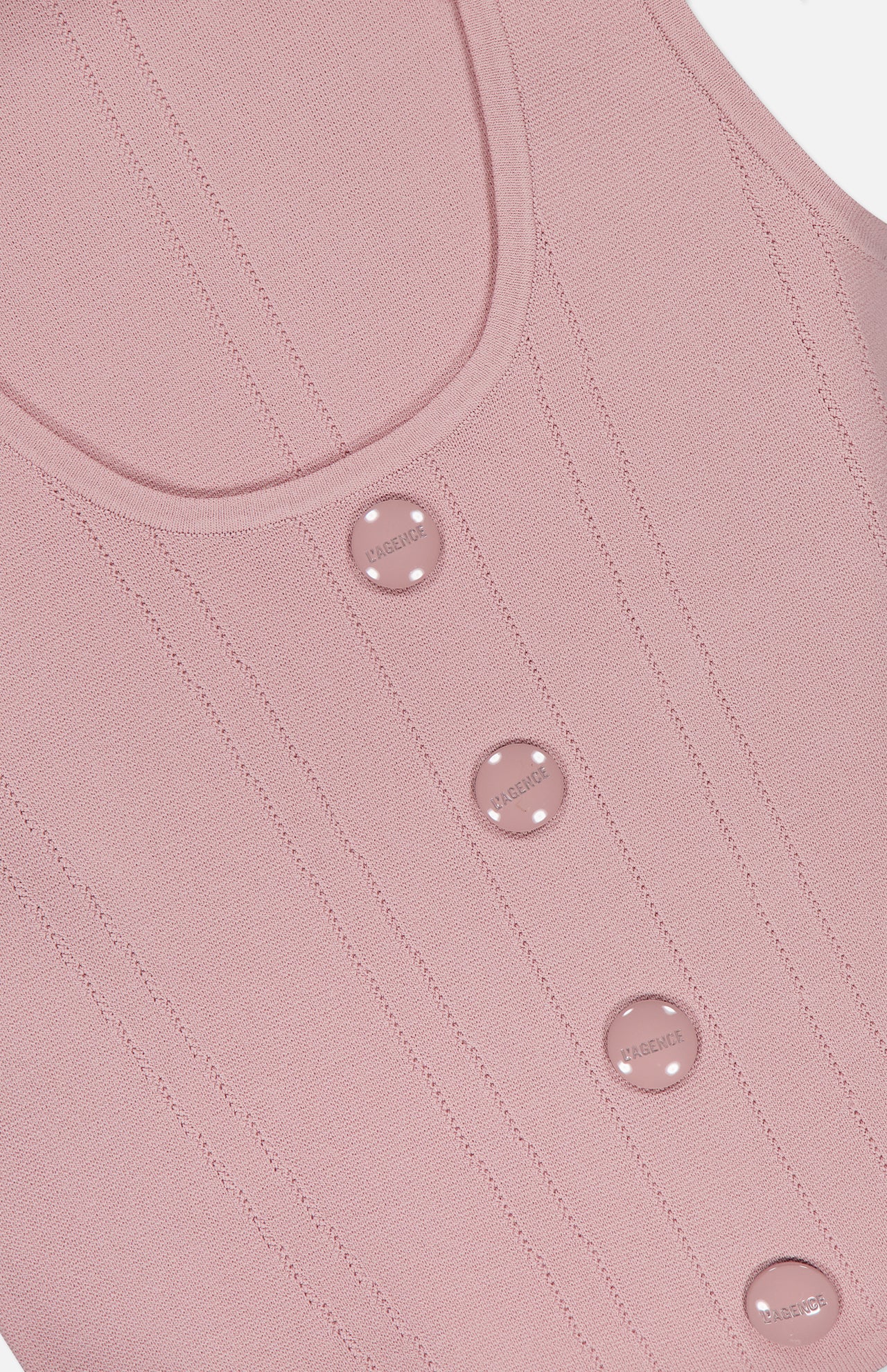 Close-up of the Dove Scoop Neck Knit Corset Top by L'AGENCE, a sleeveless pale pink power knit with vertical stitching and four round pink buttons embossed with “MUSIER” down the front.