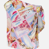 The Driselle Scarf Top by L'AGENCE features a pink design with a gold-tone buckle and a vibrant summer vacation print of vintage postcard beaches, resorts, and umbrellas in pastel pink, blue, and yellow.
