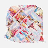 The Driselle Scarf Top by L’AGENCE showcases a pink design with a diagonal grid of vintage-style travel postcards and illustrations—women in hats, beaches, landmarks, and scenic views—making it an ideal summer vacation piece.