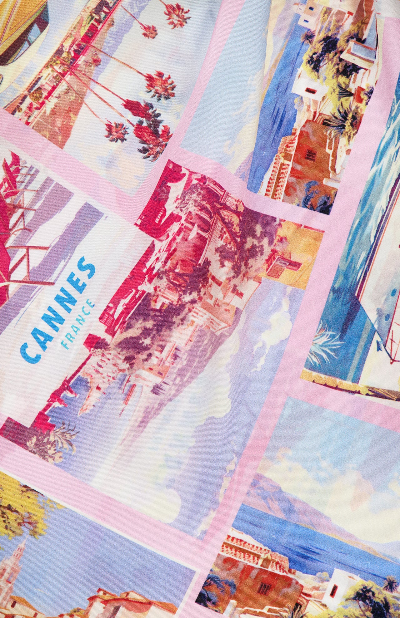 The Driselle Scarf Top by L'AGENCE features a vibrant summer print with vintage Cannes postcard illustrations—palm trees, beaches, and a pool—framed in pink and blue, perfect for your next getaway.