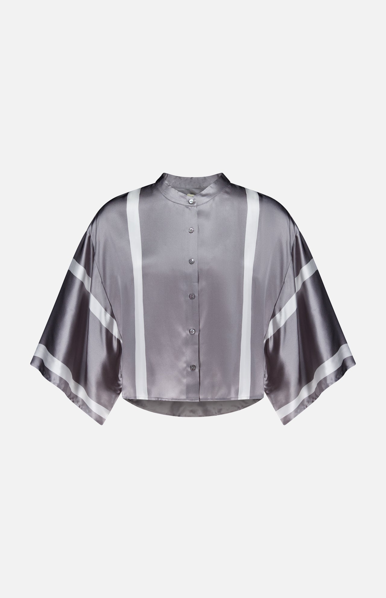 The Dru Mandarin Crop Blouse by L'AGENCE is a metallic silver satin, cropped button-front shirt with kimono sleeves and white vertical and diagonal stripe accents, shown on a plain white background.