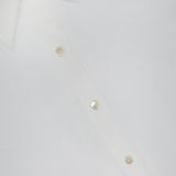 Close-up of the L'AGENCE Ellery Long Sleeve Sheer Blouse, a versatile women's top in white, featuring part of the collar and pearl-like buttons along the front placket.