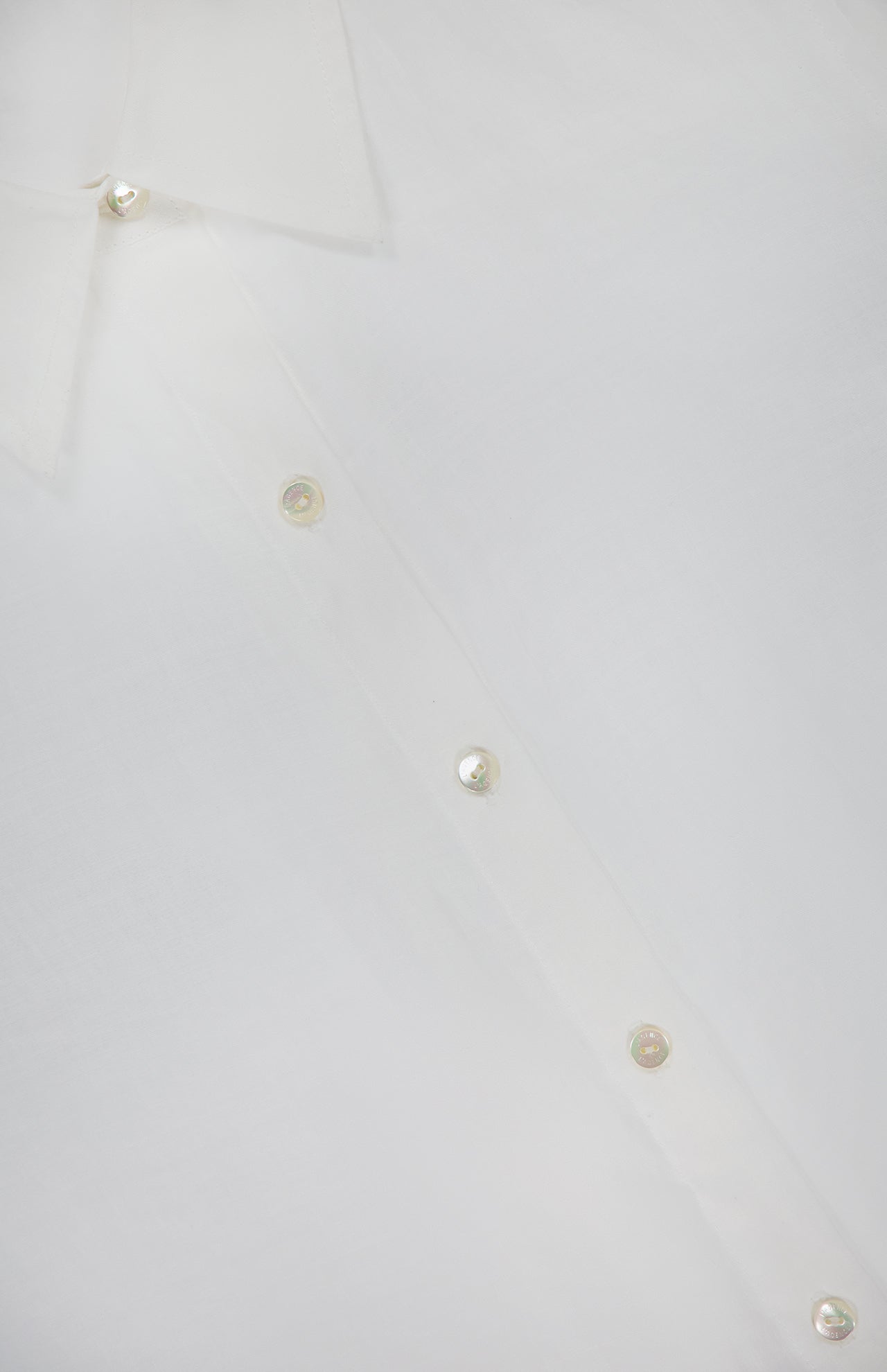 Close-up of the L'AGENCE Ellery Long Sleeve Sheer Blouse, a versatile women's top in white, featuring part of the collar and pearl-like buttons along the front placket.
