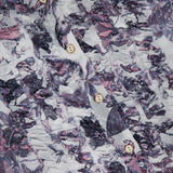 Close-up of the Eunice Ruffle Sleeve Blouse by L’AGENCE, featuring crinkled chiffon with a purple and white abstract floral print and vertical rows of beige buttons for a layered, dimensional look.
