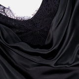 Close-up of the L’AGENCE Evadne Cowl Neck Tank Top, featuring black satin fabric draped over intricate lace detailing and showcasing the top’s shiny, smooth satin texture.