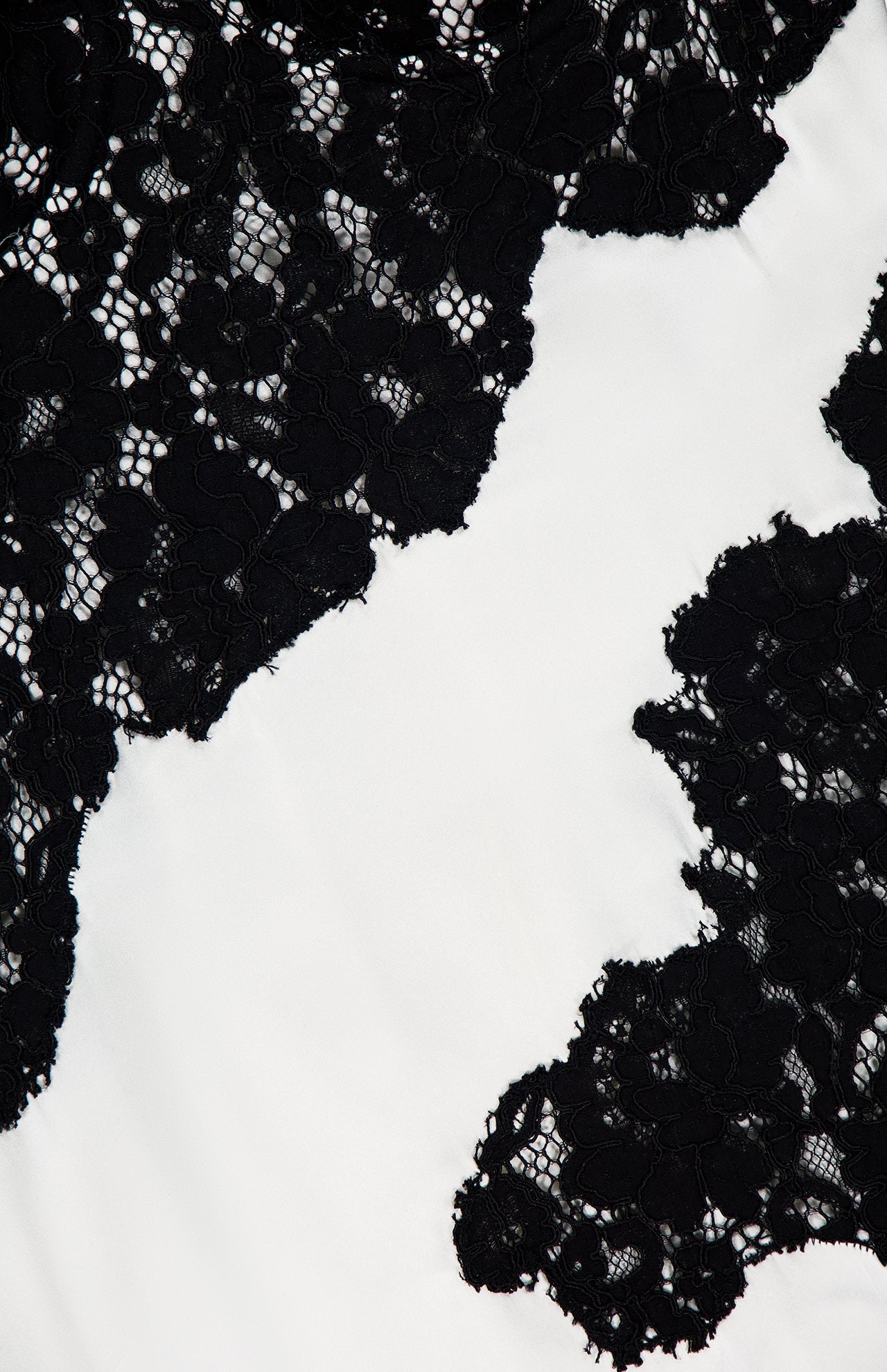 Close-up of the black floral lace on the Fenna Lace Applique Dress by L'AGENCE, featuring intricate patterns over a white backdrop, evoking the elegant contrast of this refined piece.