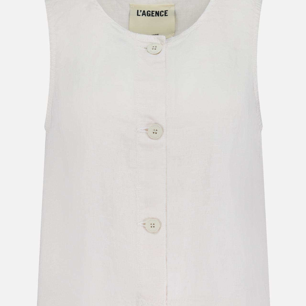 The Foster Sleeveless A-Line Top by L’AGENCE is a white linen tank with a round neckline, button-front detail with four front buttons, and features a visible L’AGENCE label inside the collar.