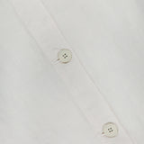 Close-up of the Foster Sleeveless A-Line Top by L'AGENCE in white linen, featuring three white buttons on the front placket with visible fabric texture and stitching details.