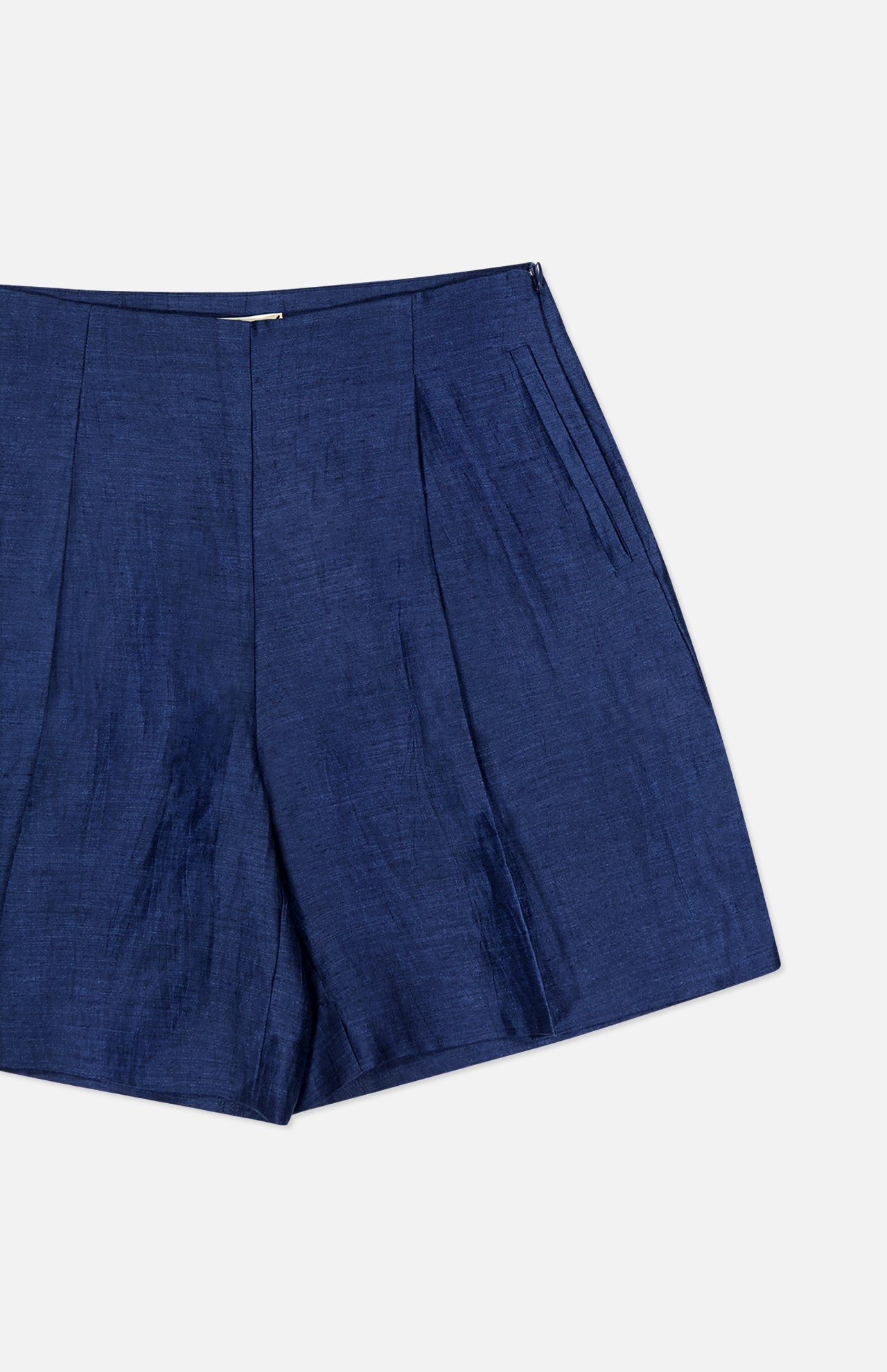 The Hadleigh Long Linen Short by L'AGENCE features a dark blue linen blend, high rise, shiny finish, front pleats, and a side zipper closure, shown against a plain white background.