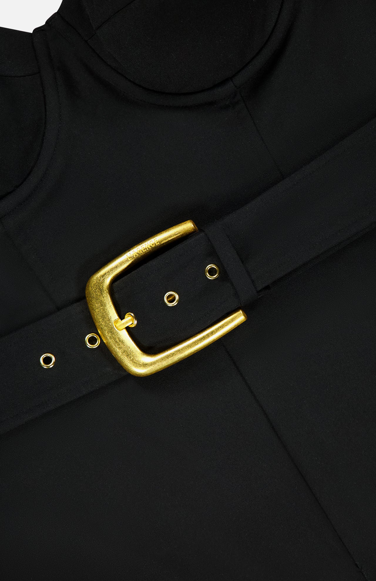 Close-up of the Jessa Bustier Tailored Jumpsuit by L'AGENCE, featuring a smooth black fabric, adjustable straps, visible tailored seams, and a wide black belt with a large shiny gold buckle and eyelets.