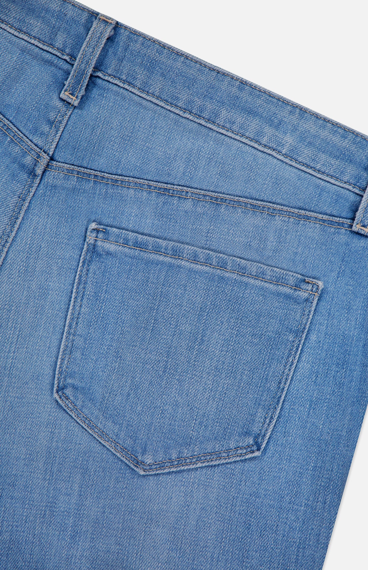 Close-up of the back pocket and waistband of the L'AGENCE Joanne Low Rise Wide Leg Jean in Pacific, highlighting the stitching and textured light blue denim against a white background.