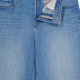 Close-up of L'AGENCE Joanne Low Rise Wide Leg Jean in Pacific, featuring light blue vintage denim with the zipper and button fly open, showing the waistband label and pocket lining.