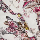 Close-up of the Kiersten Long Puff Sleeve Dress by L'AGENCE in white, featuring a butterfly, flower, and leopard print with gold buttons on the placket for an elegant touch.