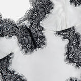 Close-up of the Kimber Lace Insert Cami by L'AGENCE, a white satin camisole with black floral lace trim, delicate eyelash edges, and adjustable straps for a perfect fit.
