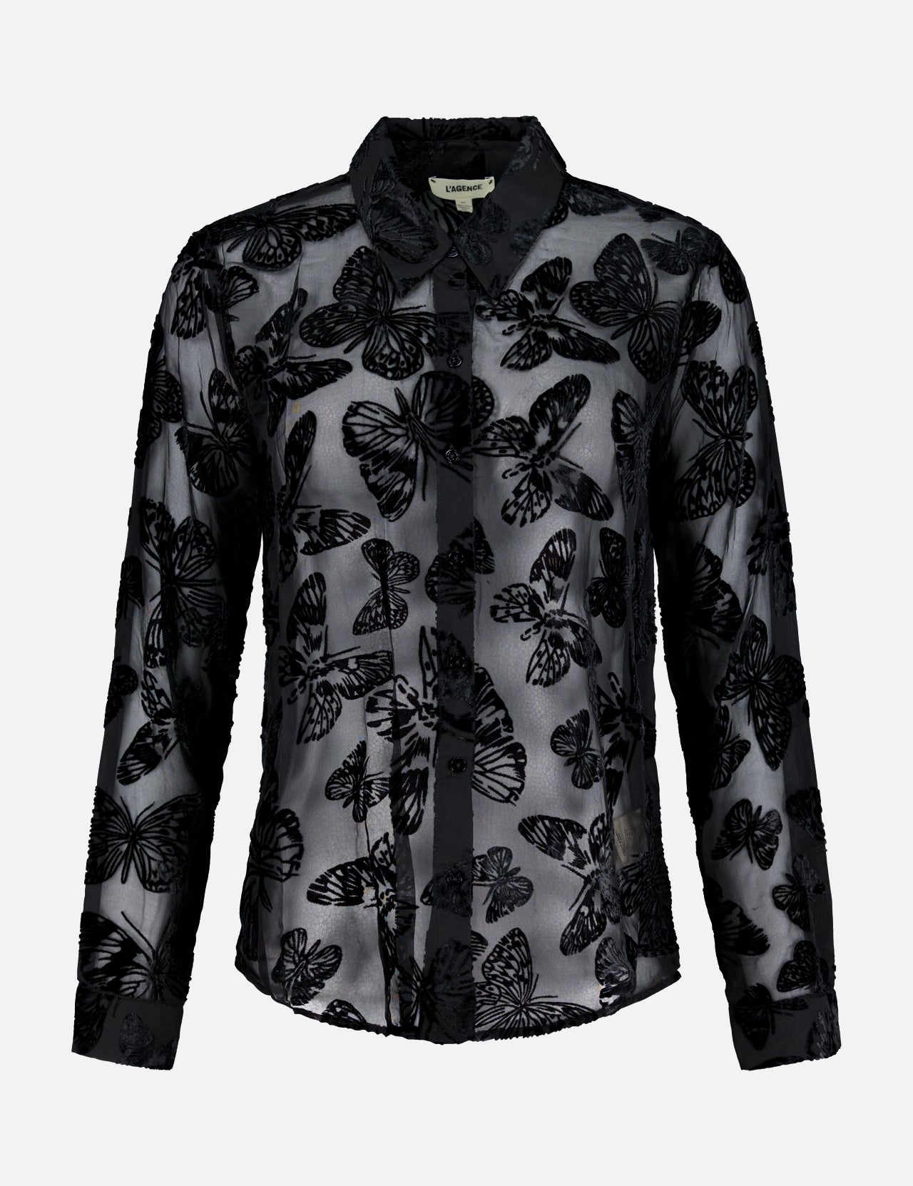 The Laurent Button Up Butterfly Blouse by L’AGENCE is a sheer black statement top with long sleeves, showcasing an all-over butterfly pattern in a striking burnout velvet design and finished with a classic collar, displayed on a plain white background.