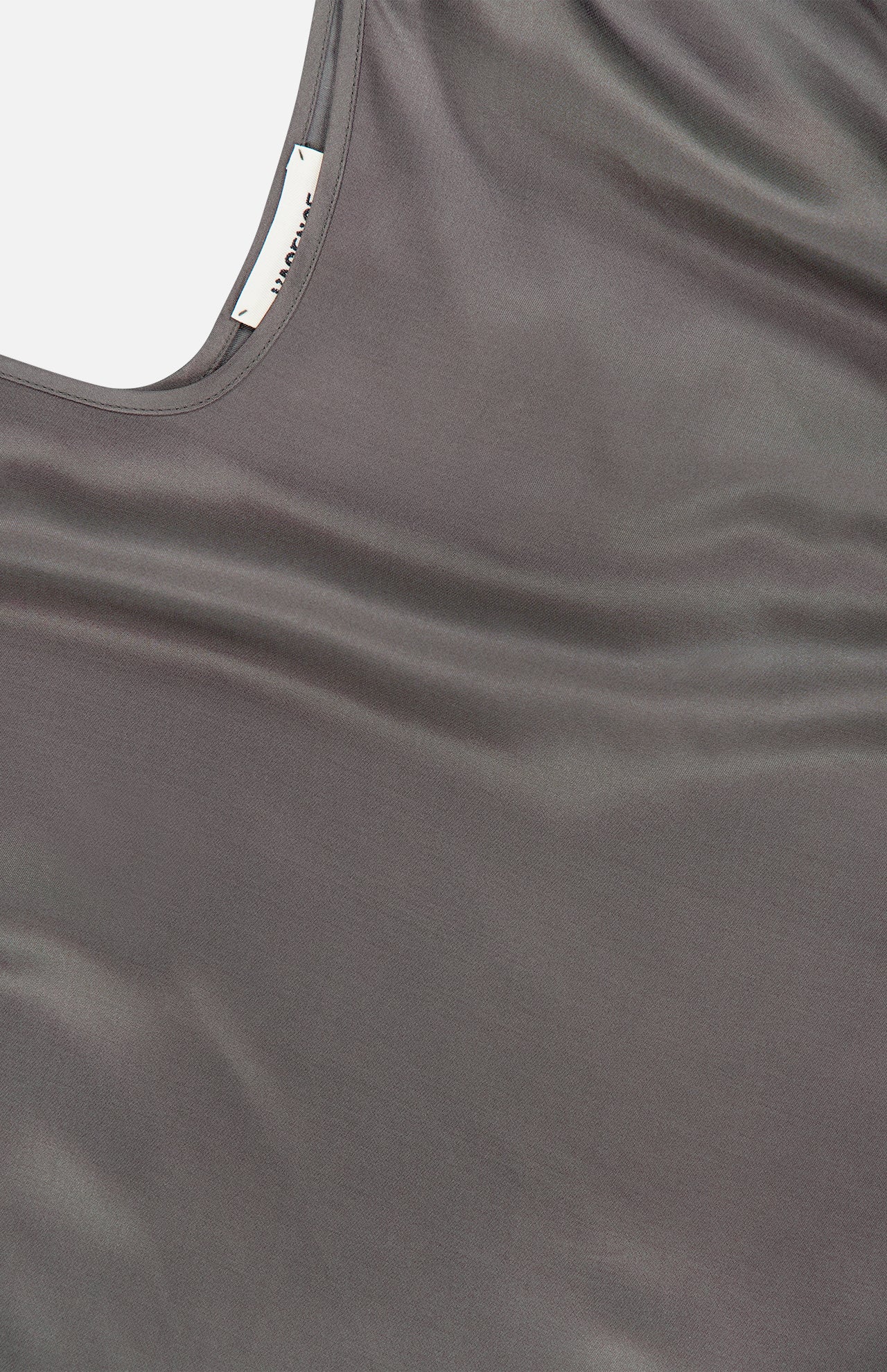 A close-up of the Lexi Silk Charmeuse Camisole by L’AGENCE, featuring soft gray silk, a scoop neckline, adjustable straps, and a visible inner tag.