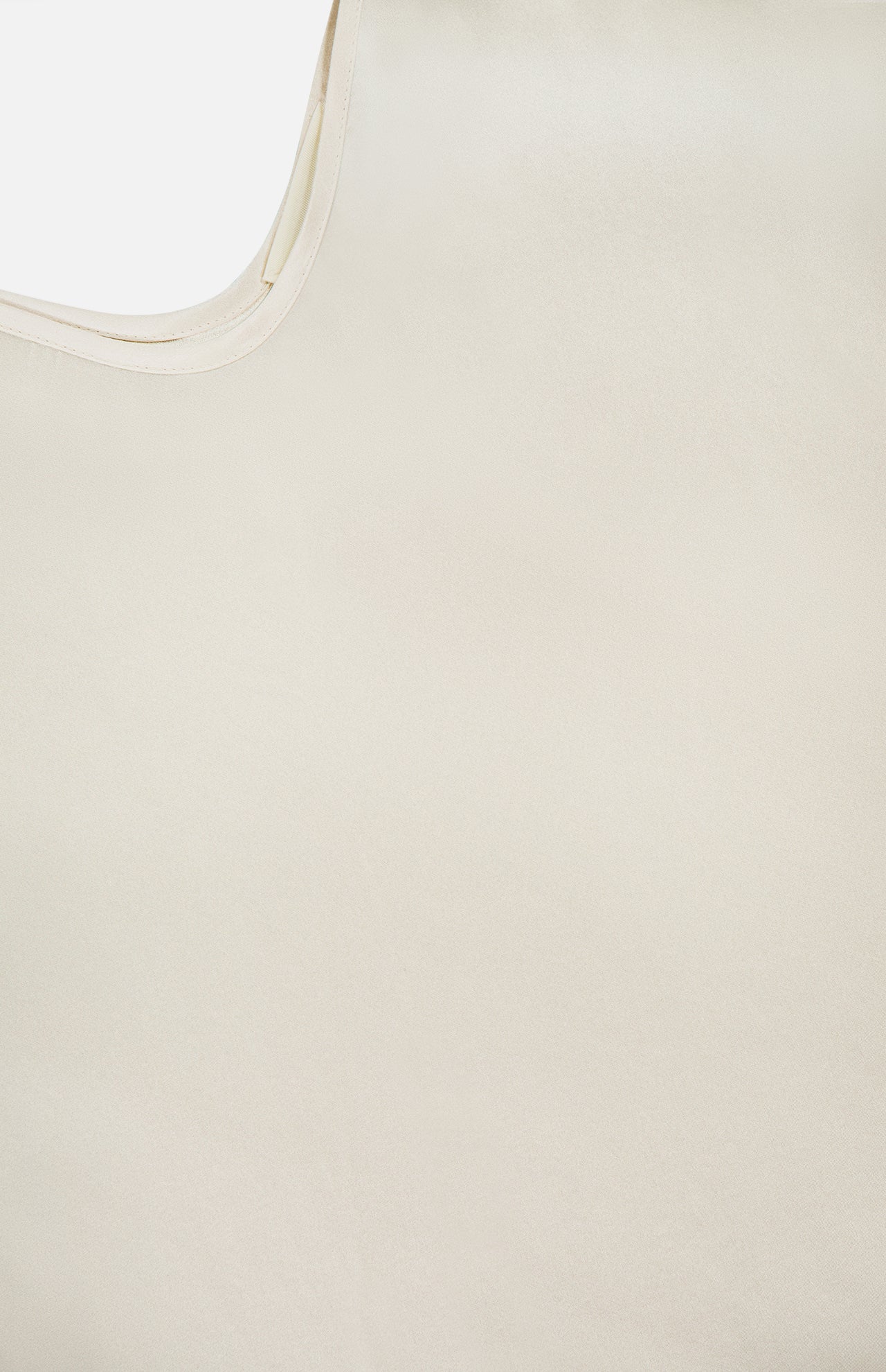Close-up of the Lexi Silk Camisole by L'AGENCE in light beige pearl, highlighting its silky texture, subtle sheen, curved edge, and smooth finish that embody the elegance of this delicate camisole.