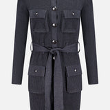 The Lore Cargo Pocket Cardigan by L'AGENCE is a long-sleeved, dark grey knit dress with four front flap pockets, large silver buttons, and a matching self-tie waist belt.