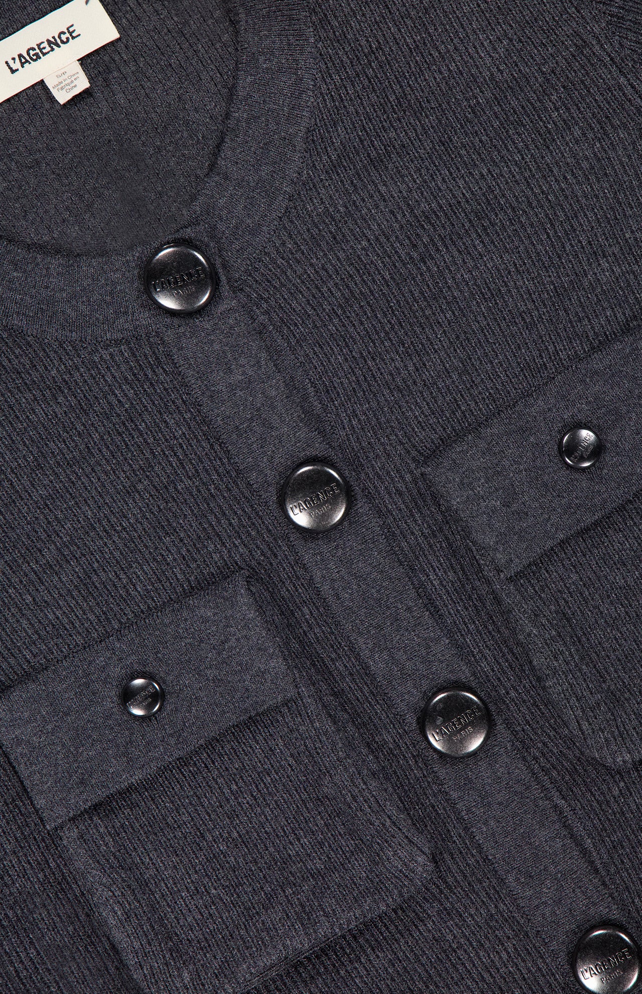 Close-up of the Lore Cargo Pocket Cardigan by L’AGENCE in dark gray knit, featuring black buttons, two front flap pockets, and a brand label at the neckline for a cozy, modern look.
