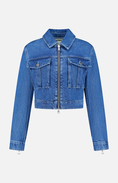 The Micah Oversized Denim Jacket by L’AGENCE is featured on a plain white background. This trendy blue denim jacket features long sleeves, a cropped silhouette, front zipper closure, and two chest pockets with flaps and buttons—delivering a stylish update to the classic denim jacket style.
