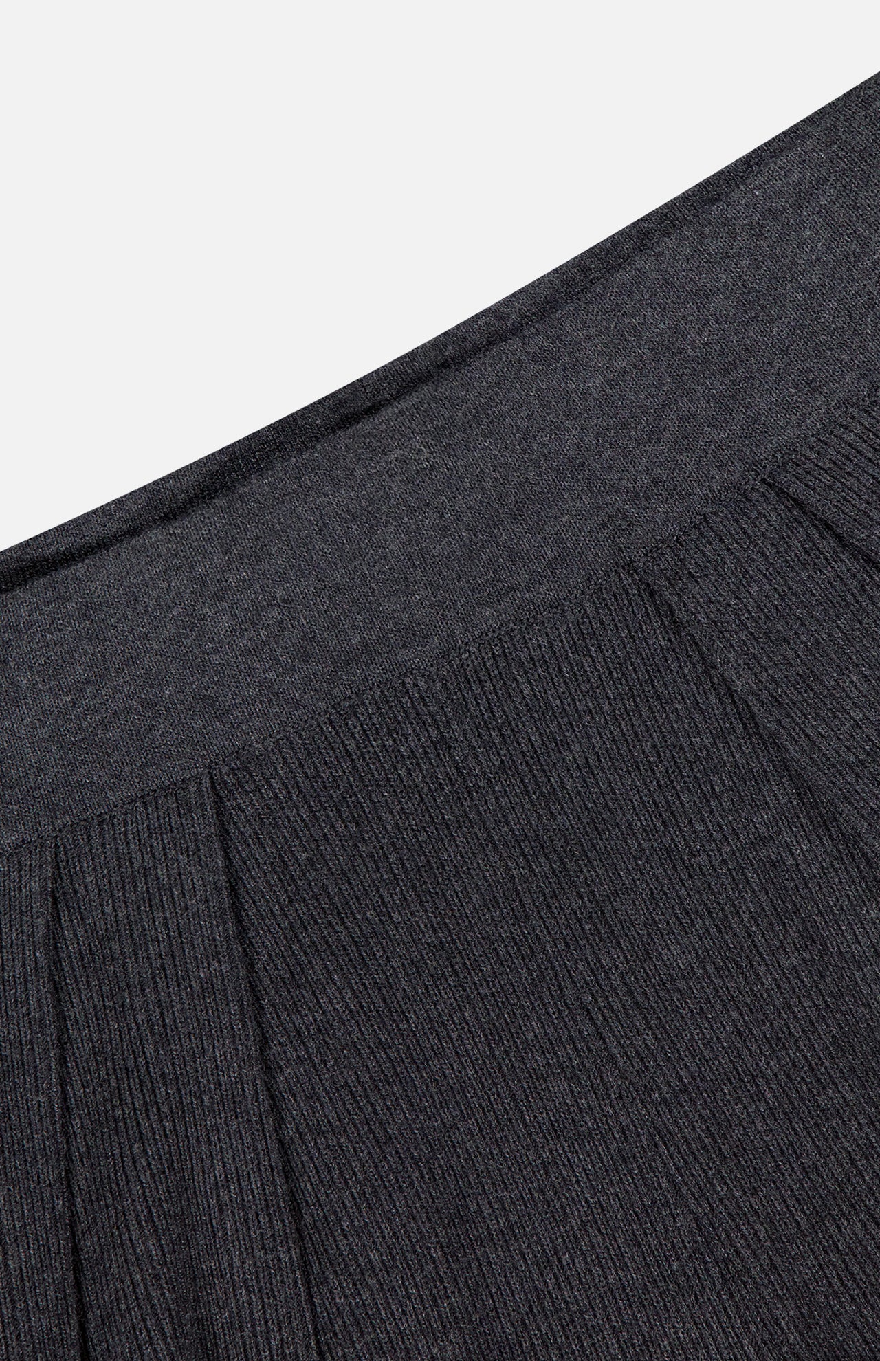 Close-up of the waistband and upper section of the Milly Draped Knit Pant by L'AGENCE in dark grey, highlighting the ribbed texture and pleating details, set against a plain light background.