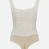 The Mixie Ruched Bodysuit by L'AGENCE features beige and vintage white mesh, wide shoulder straps, and a fitted, gathered front design, shown on a plain white background.
