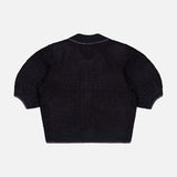 The Novalie Waffle Stitch Short Sleeve Cardigan by L’AGENCE is a black, textured feminine knit sweater featuring short sleeves and ribbed cuffs, neckline, and hem, displayed laid flat with the back facing up on a white background.