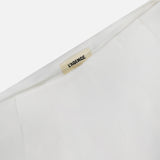 Close-up of a white garment with a beige L’AGENCE label sewn into the collar. Style it with the Novalynn Cropped Pleated Pant by L'AGENCE for a chic look. The background is plain white.