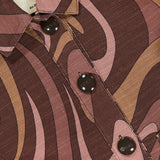 Close-up of the Nyx Cropped Swirl Print Jacket by L'AGENCE, showcasing sepia tones with swirling pink patterns, black buttons, and a visible label on the inside collar.