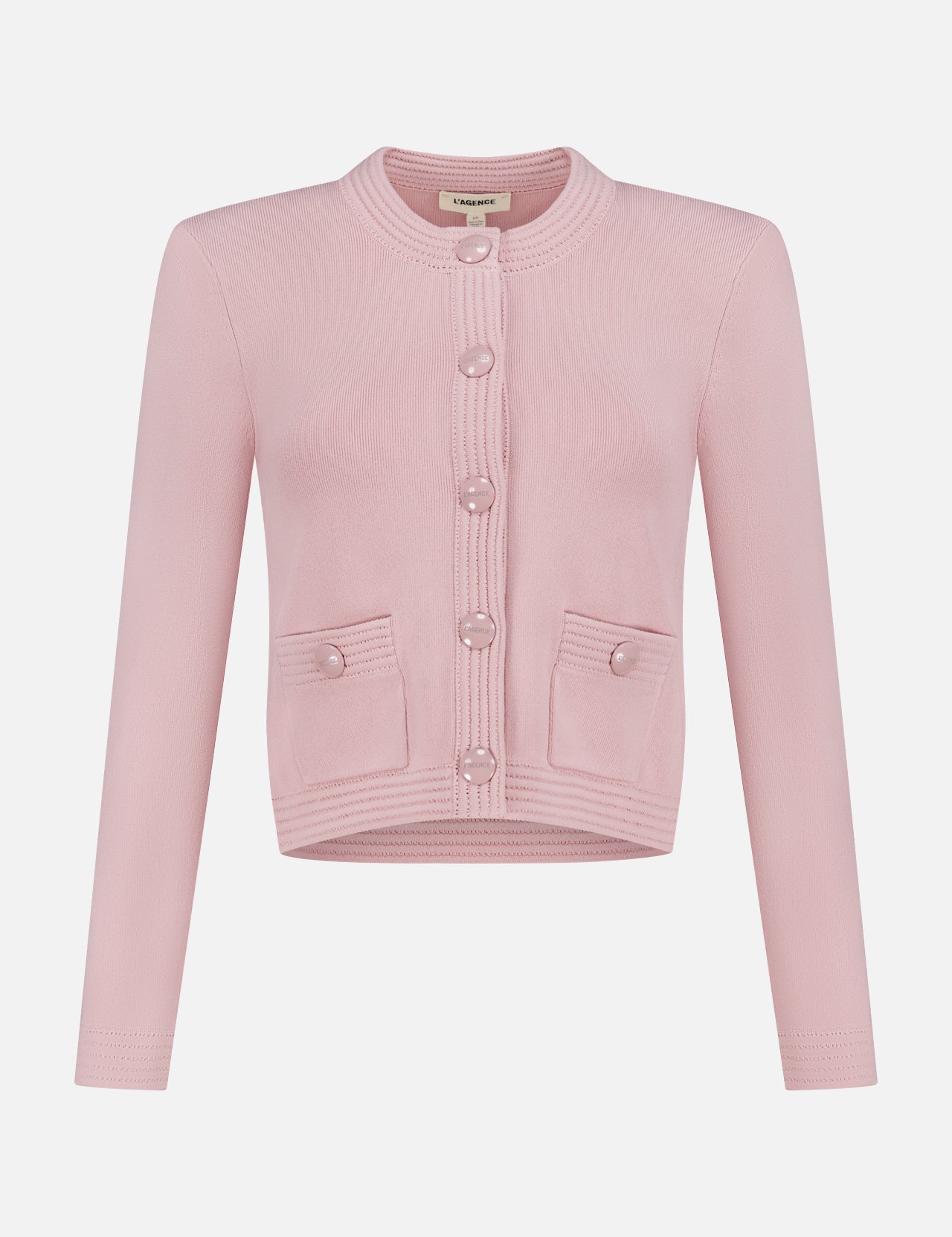 The Patsy Crop Crewneck Cardigan by L'AGENCE is a blush pointelle knit with long sleeves, a round neckline, front buttons, and two small front pockets, shown on a plain white background.
